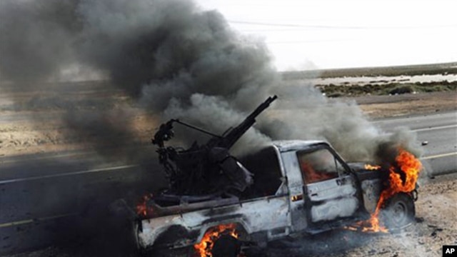 A pro-Moammar Gadhafi anti-aircraft machine gun is burned by Libyan rebels during a battle, in the town of Brega, east of Libya, March 2, 2011