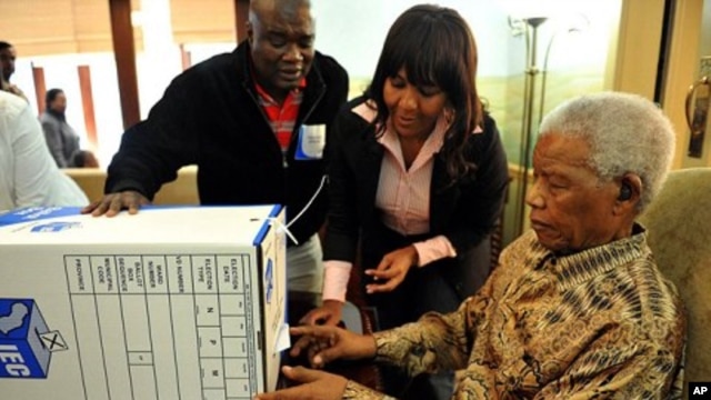 Former president Nelson Mandela, assisted by his grand daughter Ndileka Mandela and an IEC official, casts his special vote for the local government elections at his home in Houghton, Johannesburg, May 16, 2011