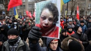 Người biểu tình cầm ảnh của nhà báo Tetyana Chornovil bị đánh đập và bỏ trên một cái hào chỉ vài tiếng đồng hồ sau khi bà cho đăng một bài báo nói về tài sản của các viên chức hàng đầu trong chính phủ, 25/12/13
