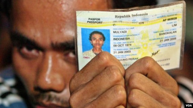 Seorang TKI asal Indonesia menunjukkan kartu tanda identiasnya sembari menunggu petugas imigrasi memeriksa dokumennya dalam sebuah razia di Klang, pinggiran Kuala Lumpur (foto: dok).