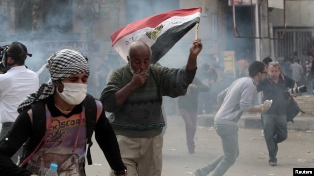 Anti-Morsi protesters run for cover during clashes with riot police at Tahrir Square in Cairo, November 27, 2012. 
