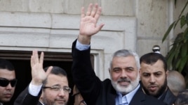 Le Premier ministre égyptien Hesham Kandil (à g.) salue la foule à Gaza City en compagnie du Premier ministre du Hamas, Ismail Haniyeh