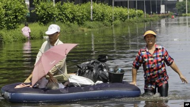 Thai people wade through a flooded area at Don Muang district in Bangkok, Thailand, October 23, 2011.