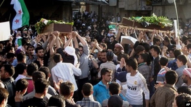 In this Saturday, April 21, 2012 photo, Syrians carry the bodies of an infant, Adam al Najjar, and Free Syrian Army fighter, Mowaffaq al Nablsi, 42, during their funeral in Douma, a suburb of Damascus, Syria.
