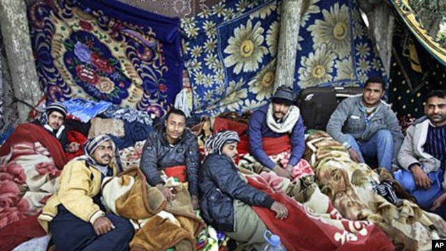 Egyptian migrant workers lie under blankets in a makeshift open-air camp at Tripoli International Airport in Libya, March 1, 2011