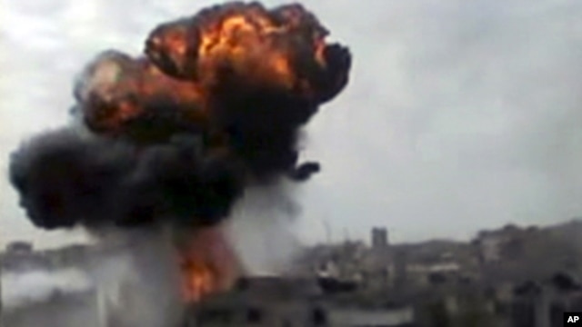 In this image made from amateur video released by the Shaam News Network and accessed Sunday, April 15, 2012, smoke billows an impact following purported shelling in Homs, Syria. 