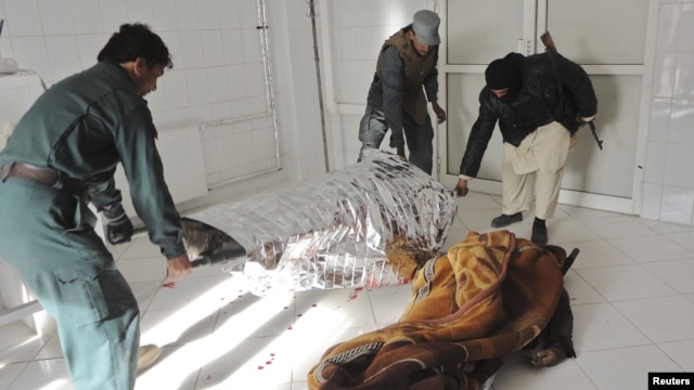 Afghan policemen carry the dead body of a victim at a local hospital after a suicide bomb attack in Khost province, December 26, 2012.