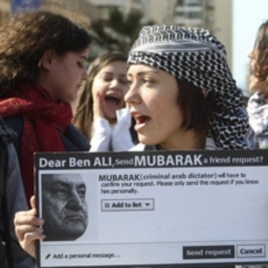A protester carries a sign referring to ousted Tunisian President Zine al-Abidine Ben Ali and Egypt's President Hosni Mubarak during a demonstration against Mubarak in front of the Egyptian Embassy in Beirut, Feb 5, 2011