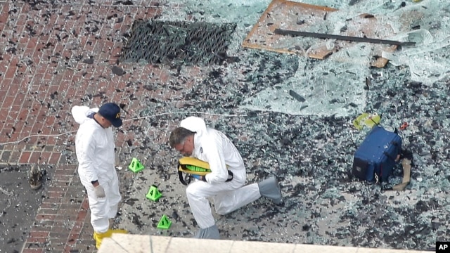 Two men in hazardous materials suits put numbers on the shattered glass and debris as they investigate the scene at the first bombing on Boylston Street in Boston, Apr. 16, 2013.