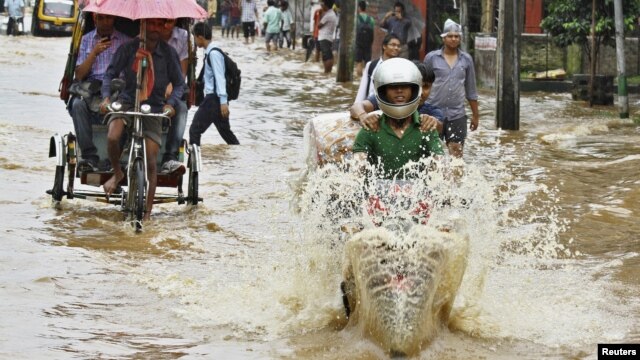 Commuters travel through a flooded street after heavy rains at Guwahati, in the northeastern Indian state of Assam, June 26, 2012. 