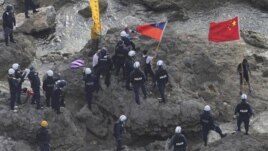 Chinese activists holding the flags of China and Taiwan are arrested by Japanese police officers on one of the disputed islands on August 15, 2012.