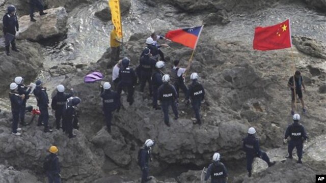 Chinese activists holding the flags of China and Taiwan are arrested by Japanese police officers on one of the disputed islands on August 15, 2012.