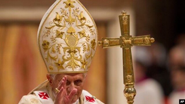 Pope Benedict XVI delivers his blessing as he leaves after celebrating Christmas Mass in St. Peter's Basilica at the Vatican, December 24, 2011.