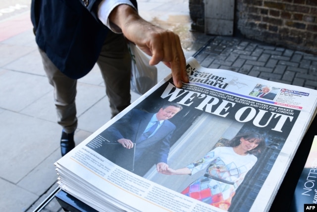 A man takes a copy of the London Evening Standard with the front page reporting the resignation of British Prime Minister David Cameron and the vote to leave the EU in a referendum on June 24, 2016.