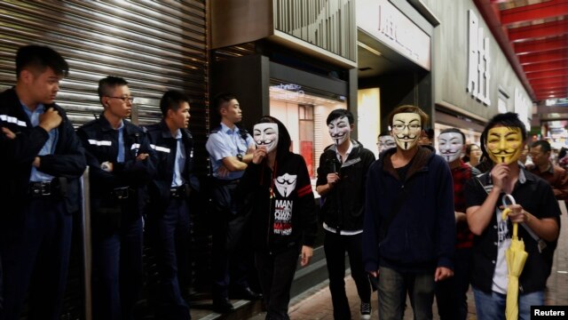 Người biểu tình đòi dân chủ mang mặt nạ Guy Fawkes đi ngang qua cảnh sát trên con đường bị chiếm đóng ở khu vực Mongkok, Hong Kong, ngày 5/11/2014.