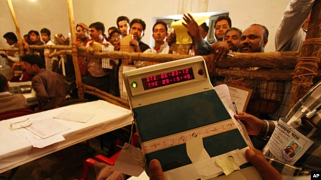 An election official shows an electronic voting machine to poll agents at a counting station in Lucknow, India, March 6, 2012.