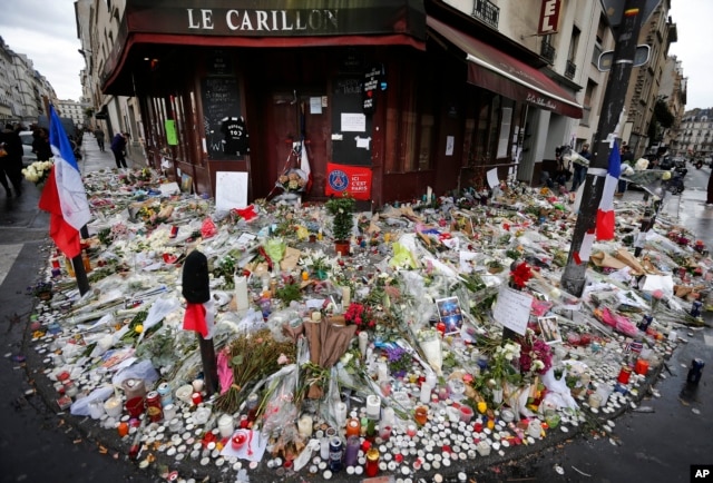 FILE - Flowers and candle tributes are placed at the Restaurant Le Carillon in Paris, Nov. 19, 2015, after the deadly terror attacks.