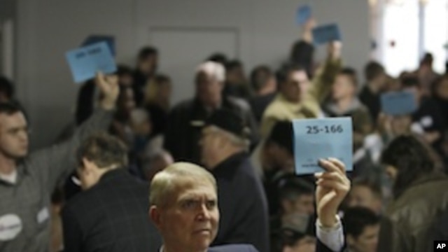 Bill Barnson, left, and others staffing precinct tables at a Washington state Republican caucus meeting, hold up signs showing precinct numbers, Saturday, March, 3, 2012, in Puyallup, Washington. 