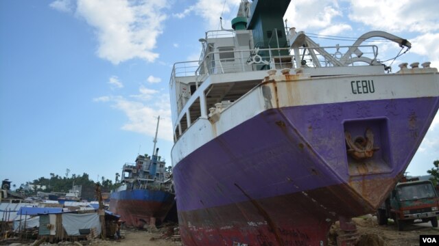 Beached ships among shanties along this seaside community of Anibong. The city says shipping companies have been given months to remove the ships, if not the government will move them, Tacloban City, Philippines, March 9, 2014. (Simone Orendain for VOA)