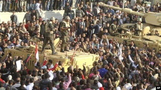 Armed soldiers look down on protesters surrounding military vehicles in Tahrir Square in Cairo, Egypt, February 2, 2011