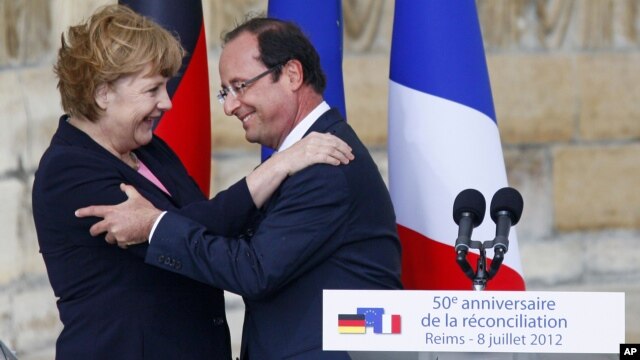 German Chancellor Angela Merkel, and French President Francois Hollande react after a speech in front of the Reims cathedral in Reims, eastern France, July 8, 2012. 