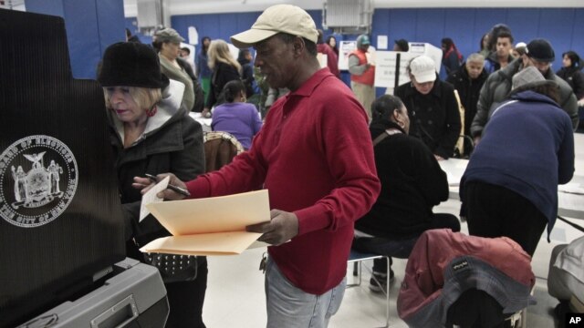 A poll worker assists a voter arriving from a relocated polling site that closed after flooding from superstorm Sandy on Manhattan's Lower East Side in New York, November 6, 2012.