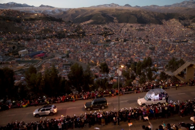 Pope Francis rides in his popemobile, right, as he greets people lining the road from El Alto to La Paz, upon his arrival to Bolivia, Wednesday, July 8, 2015.