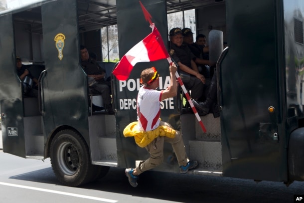 A man jumps onto a police vehicle during a rally of indigenous people protesting against the pollution resulting from oil production in the Amazons region, in Lima, Peru, Nov. 18, 2016. The capital is hosting the Asia Pacific Economic Cooperation or APEC.