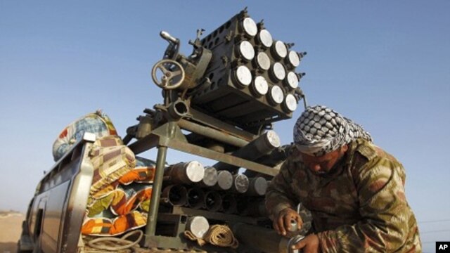 A rebel fighter scrubs his missiles at a front line checkpoint on the road between Bin Jawad and Nawfiliyah, Libya, March 29, 2011