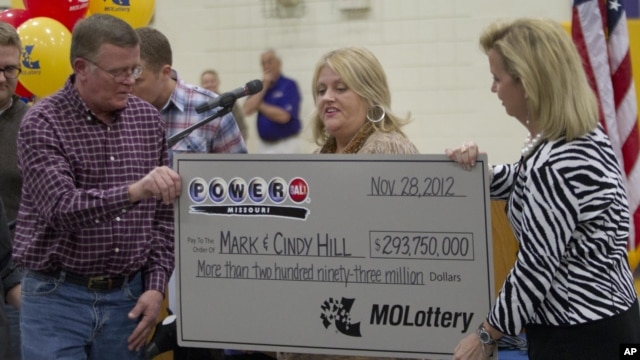 Mark, left, and Cindy, center, Hill are presented a check by a Missouri Lottery official during the announcement of Powerball winners in Dearborn, Missouri, November 30, 2012. 