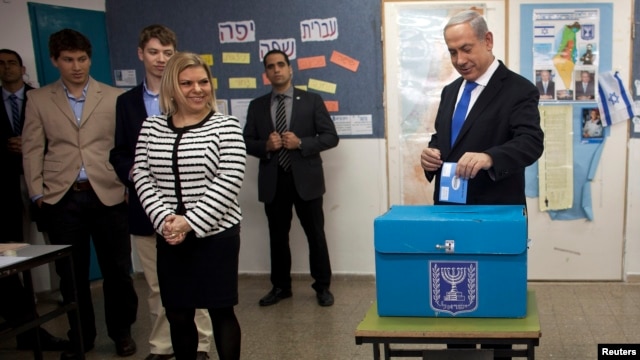 Israel's Prime Minister Benjamin Netanyahu (R) casts his ballot for the parliamentary election as his wife Sara (3rdL) stands nearby at a polling station in Jerusalem, January 22, 2013.