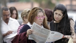 Voters read the a sample ballot as they wait in line to cast their vote in Hialeah, Florida, November 6, 2012.