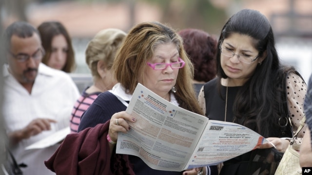 Voters read the a sample ballot as they wait in line to cast their vote in Hialeah, Florida, November 6, 2012.
