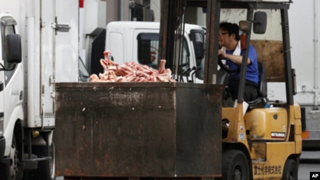 A worker operates a forklift, carrying a container loaded with a pile of bones of beef, at a wholesale meat market in Tokyo, July 12, 2011