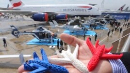 An Airbus employee presents three model airplanes in blue, white and red, made from starch using a 3D printing technique during the opening of 50th Paris Air Show, at the Le Bourget airport near Paris, June 17, 2013. In the future the company hopes to use
