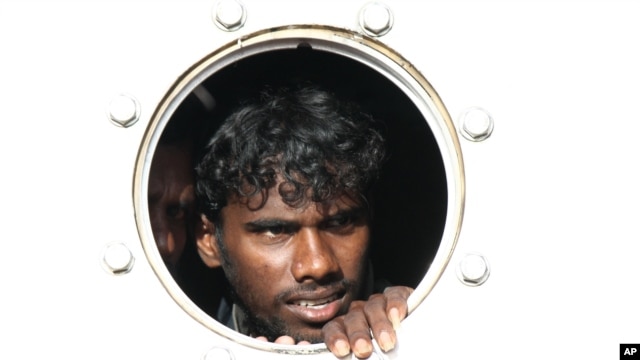 A Sri Lankan asylum seeker who was rescued from a troubled boat adrift trying to reach Australia looks out from a porthole of a rescue ship upon arrival at Teluk Bayur port in Padang, West Sumatra, Indonesia, January 2, 2013. 