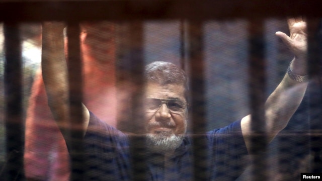 Former Egyptian President Mohamed Mursi waves as he enters for his trial with other Muslim Brotherhood members at a court in the outskirts of Cairo, May 16, 2015.