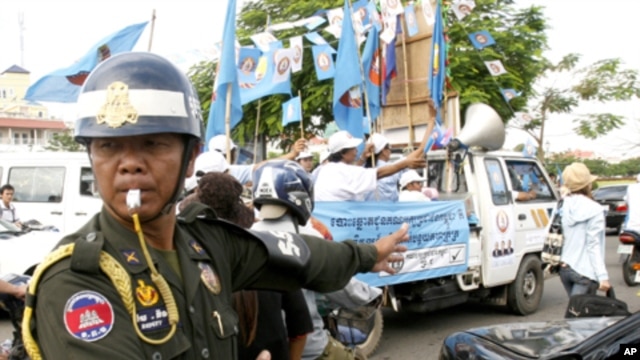 A Cambodian military police officer, left, traffics during the election campaign in Phnom Penh, file photo. 