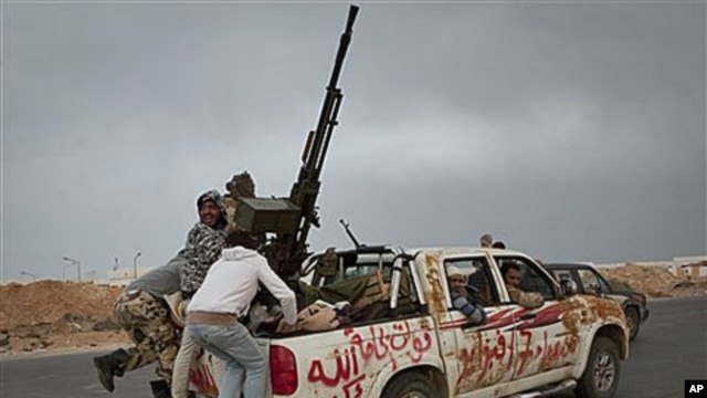 Libyan rebels jump onto back of their vehicle as they leave Ras Lanouf in central Libya after Gadhafi's forces drove rebels out of Bin Jawwad, a hamlet east of Sirte, March 29, 2011