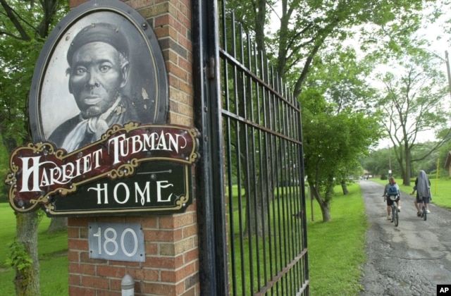 FILE - Children ride their bikes down the drive passing the Harriet Tubman Home in Auburn, N.Y. The home of the abolitionist is along a trail of memorials and museums from New England south to Washington, D.C., that extol women's achievements in molding t