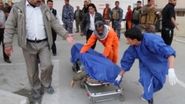 Medical personnel wheel body of victim killed by suicide bomber in Tuz Khurmato city, Jan. 23, 2013