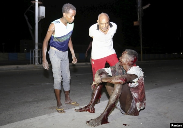 A Somali man injured in a night car bomb attack near a hotel in Hamarweyne district sits along a sidewalk near the scene in capital Mogadishu, Somalia, Feb. 26, 2016