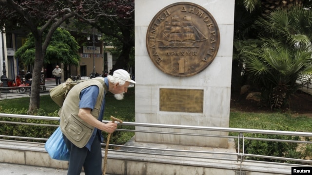 A man makes his way past a replica of a one drachma coin outside the Athens Town Hall, May 21, 2012.