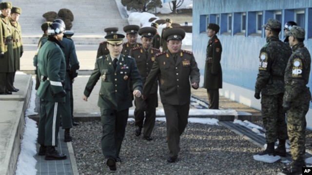 North Korean Colonel Ri Son-kwon (front R) and other North Korean delegates cross the border escorted by a South Korean solder (front L) for military talks at the truce village of Panmunjom in Paju, February 9, 2011.