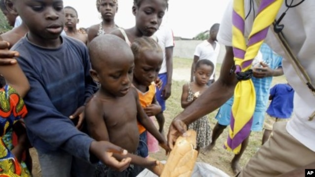 A man distributes bread to children at St. Ambrose church in Angree, Abidjan, a temporary refuge for people fleeing from clashes between forces loyal to incumbent president Gbagbo and his rival Ouattara (File Photo - March 1, 2011)