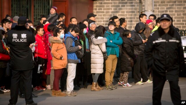 FILE - Chinese police watch as depositors from Ezubao gather in Beijing, Jan. 1, 2016. Chinese state media reported police arrested 21 employees at China's largest online finance business, Jan. 31, 2016.