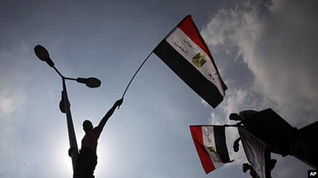 Egyptian protesters wave from lamp posts hanging their national flags at Tahrir Square, the focal point of the Egyptian uprising, in Cairo, September 9, 2011.