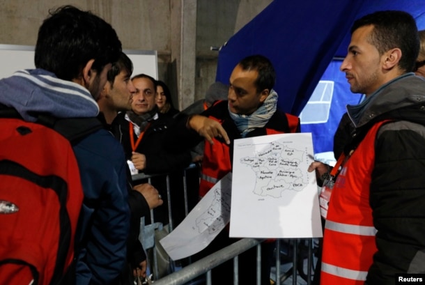 FILE - Migrants look at a map of France at a processing center to be registered on the second day of their evacuation and transfer to reception centers in France, during the dismantlement of the camp called "the Jungle" in Calais, France, Oct. 25, 2016.