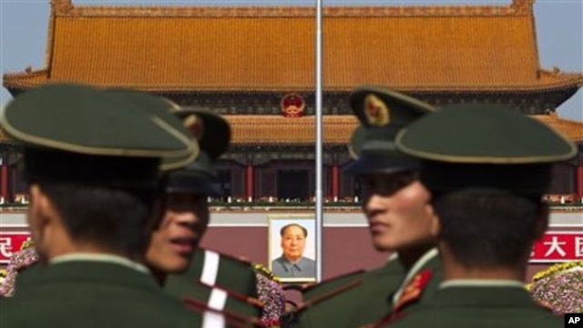 Paramilitary policemen look back while patrolling on the Tiananmen Square in front of the late communist leader Mao Zedong's portrait in Beijing, China, 15 Oct. 2010