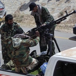 Libyan rebels maintain a heavy machine gun mounted on top of a pickup truck during an exchange of fire with pro Gadhafi forces, outside the eastern town of Brega, Mar 31 2011